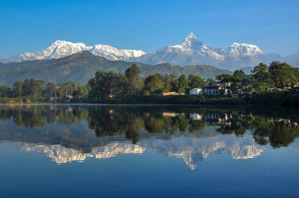 pexels-photo-14989384-14989384 Stunning reflection of the Annapurna mountains in Phewa Lake, Pokhara, showcasing natural beauty.